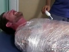 Jock Clint wrapped up to have his feet tickled BDSM style